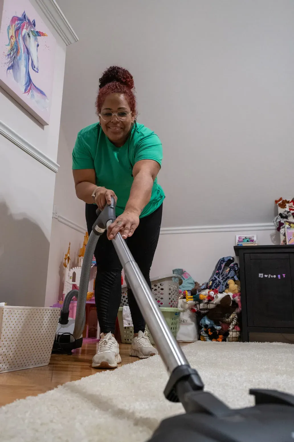 Team member vacuuming a bedroom carpet during a recurring visit