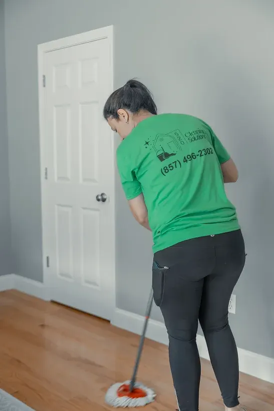Integrante del equipo trapeando un piso de madera