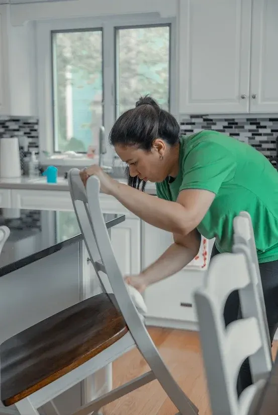 Team member cleaning a kitchen chair, rung by rung