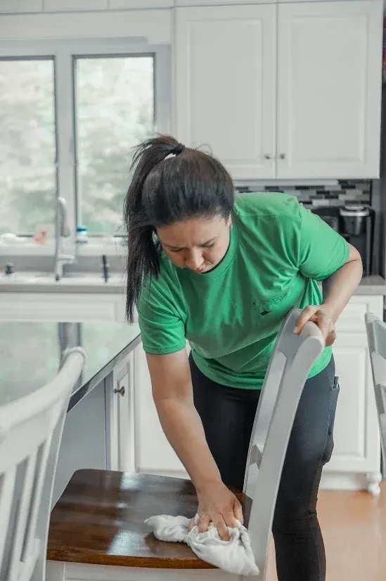 Integrante del equipo limpiando una silla de cocina durante una visita recurrente