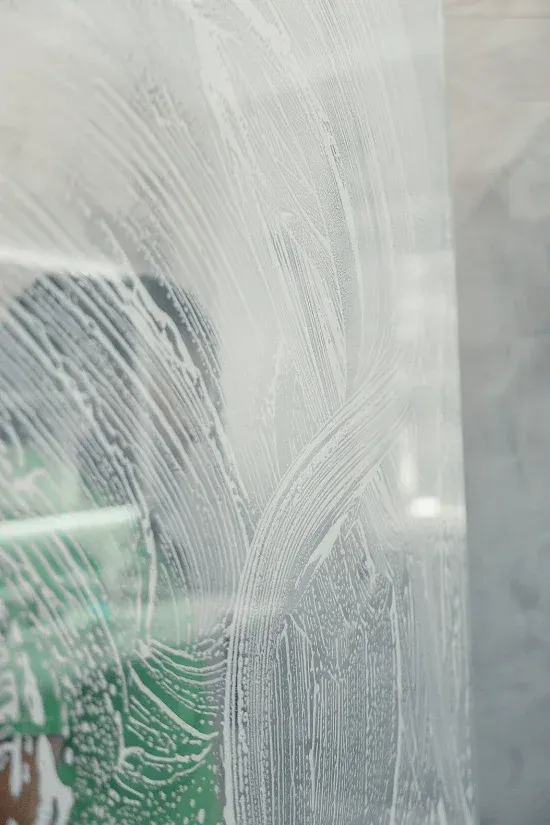 Glass shower door being scrubbed with soap